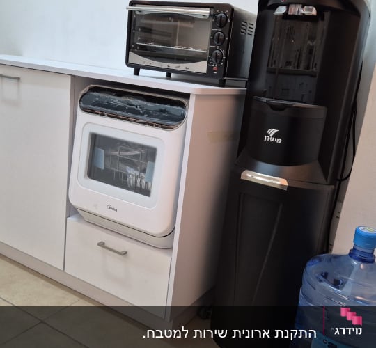 תנור קטן על ארון מטבח ליד מתקן מים